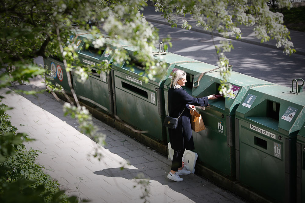 Kvinna lämnar förpackningar vid återvinningsstation